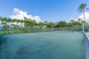 a tennis court with palm trees in the background at Beautiful Kuilima East Estates Townhome - Golf Course & Ocean Views in Kahuku