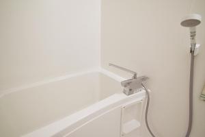 a white bath tub with a shower head in a bathroom at Hostel In Kyoto Gion - Vacation STAY 13366v in Gionmachi