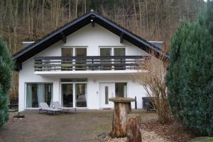 a white house with a porch and two chairs at Ferienwohnungen TalBach in Simmerath