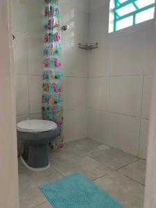 a bathroom with a toilet and a shower curtain at Casinha do pontal da cruz in São Sebastião