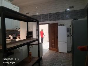 a man standing in a kitchen with a refrigerator at La villa dolive in Niamey