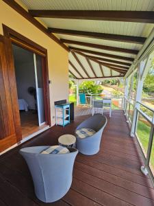 a porch with a couch and chairs on a deck at STUDIO Azur in Gourbeyre