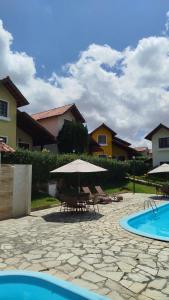 a patio with tables and umbrellas and a pool at Linda casa em Gravatá in Gravatá
