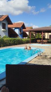 two people in the swimming pool of a house at Linda casa em Gravatá in Gravatá +7 photos