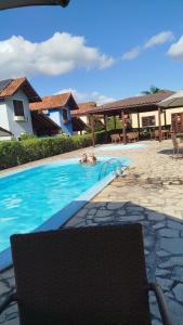 a swimming pool with a chair in front of a house at Linda casa em Gravatá in Gravatá