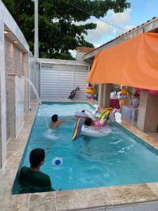 two people are playing in a swimming pool at Casa com piscina in Maceió