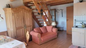 un soggiorno con una sedia rosa e una scala di Ferienwohnung Gerda Riederer a Neualbenreuth Altre 6 foto