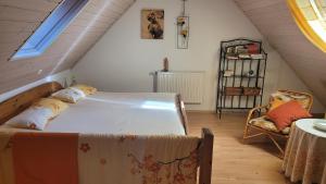una camera da letto con un letto e una sedia in mansarda di Ferienwohnung Gerda Riederer a Neualbenreuth