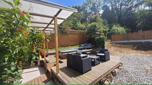 a wooden deck with chairs and a pergola at Les pléiades in Lamballe Armor