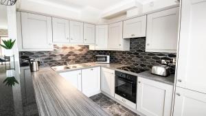 Cresent Townhouse في غالواي: مطبخ أبيض مع دواليب بيضاء ومغسلة +3 صور