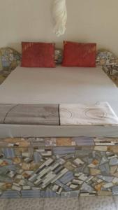 a bed with mosaic floors and red pillows on it at Campement les Antilles in Abene