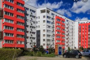 two tall buildings with cars parked in a parking lot at ARAD Chic Apartament UTA in Arad