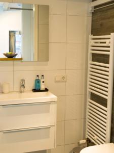 a white bathroom with a sink and a mirror at Slapen bij Scherp in Middelburg +30 photos