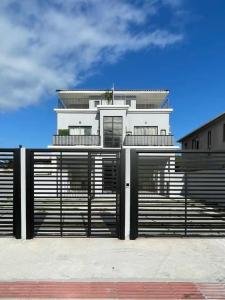 una casa blanca con puertas y una valla en Studios Montblanc Campeche, en Florianópolis