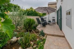a patio with an umbrella and chairs and plants at House Lucic in Zaton