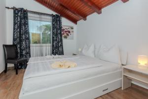 a bedroom with a white bed with a chair and a window at House Lucic in Zaton