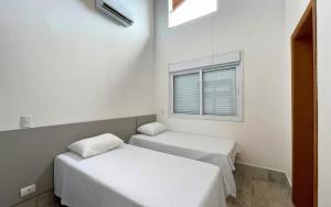 two beds in a room with a window at Casa 14 · 4 Suítes | Piscina Privativa e Serviço De Praia in São Sebastião