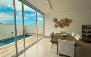 a dining room with a table and a view of the ocean at Casa 14 · 4 Suítes | Piscina Privativa e Serviço De Praia in São Sebastião