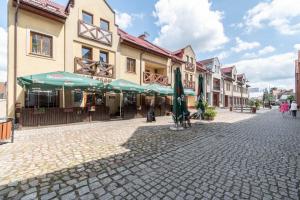 a cobblestone street with cafes and umbrellas at Apartament Mąki Gram in Złocieniec