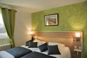 two beds in a hotel room with green walls at Logis Auberge À La Tête De Lard in La Ferté-Imbault