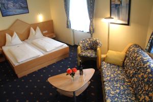 a hotel room with a bed, table, chairs and lamps at Hotel Bayrischer Hof in Wels