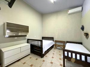 1 dormitorio con 2 camas individuales y TV en Chateau Gil em Juquehy, en São Sebastião