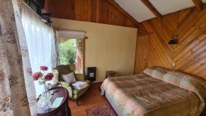 a bedroom with a bed and a chair and a window at Tranqueras del Monte in Chaitén