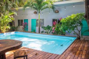 a large swimming pool with a wooden deck with a wooden table and chairs at Refugio Surf Lodge in Tamarindo
