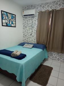 a bedroom with a bed with blue sheets and a window at Bela Casa PX as praias in São Luís +25 photos