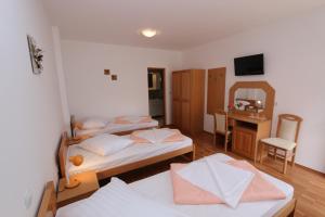 a room with two beds and a desk with a mirror at Pansion Comfort Sidro in Novalja