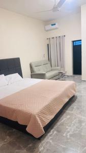 a bedroom with a large bed and a chair at Belgam Lodge in Kololi