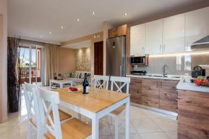 a kitchen with a wooden table and white chairs at Lia's Home One in Mantoúkion