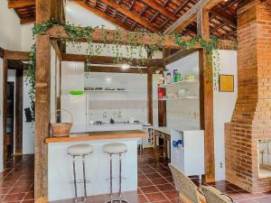 a kitchen with a counter and stools in a room at Casa Esperança Praiana - Ideal para... · Juquehy | Casa Esperança Praiana ideal p/ crianças in São Sebastião