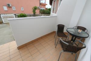 a balcony with a table and chairs and a window at Pansion Comfort Sidro in Novalja