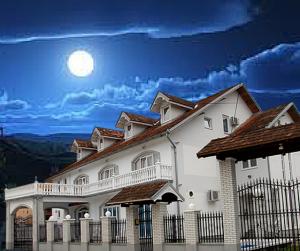 a large white house with a fence and the moon in the sky at Guesthouse Vila Nova in Morović