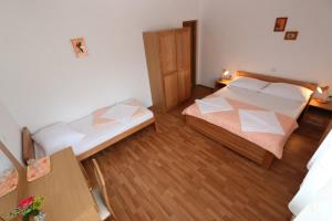 a bedroom with two beds and a wooden floor at Pansion Comfort Sidro in Novalja