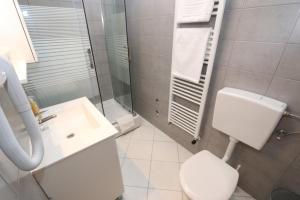 a white bathroom with a toilet and a sink at Pansion Comfort Sidro in Novalja