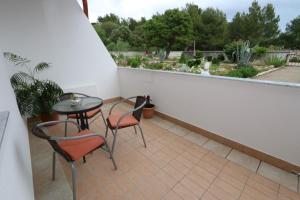 a patio with a table and two chairs and a balcony at Pansion Comfort Sidro in Novalja