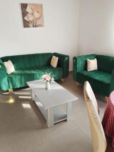 a living room with two green couches and a coffee table at Résidesnce Merveilles M18 in Kribi