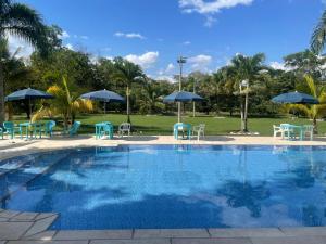a swimming pool with tables and chairs and umbrellas at Casa D`Campo Alegre in Acacías