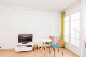 a living room with a tv and a table and chairs at L'Écrin - Studio Calme - Proche Bois de Vincennes & Métro in Vincennes