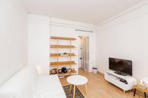 a white living room with a white couch and a tv at L'Écrin - Studio Calme - Proche Bois de Vincennes & Métro in Vincennes +1 photo