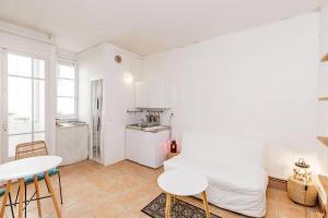 a room with a bed and two tables and a kitchen at L'Écrin - Studio Calme - Proche Bois de Vincennes & Métro in Vincennes