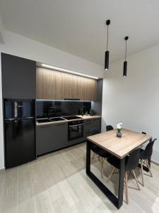 a kitchen with a wooden table and black appliances at Serenity Luxury Apartment in Alexandroupoli