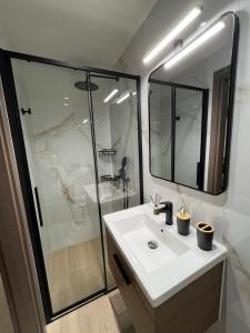 a bathroom with a white sink and a shower at Serenity Luxury Apartment in Alexandroupoli +35 photos