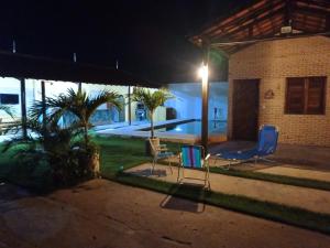 two chairs and a table in a yard at night at Chalé dos Coqueiros em Paracuru in Paracuru +32 photos
