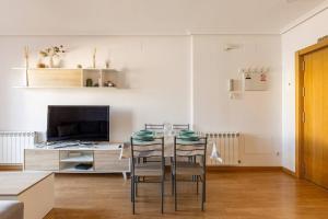 ein Esszimmer mit einem Tisch mit Stühlen und einem TV in der Unterkunft apartamento familiar con piscina licencia 14721 in Camarma de Esteruelas