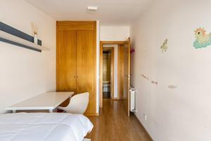 ein Schlafzimmer mit einem weißen Bett und einem Schreibtisch in der Unterkunft apartamento familiar con piscina licencia 14721 in Camarma de Esteruelas + 14 Fotos