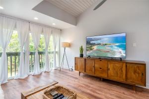 a living room with a flat screen tv on a wooden dresser at The Drifter - North Shore Loft - Relaxed Luxury in Kahuku
