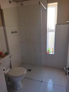 a bathroom with a toilet and a window at 21 Pin Oak Guest House in Cape Town +6 photos